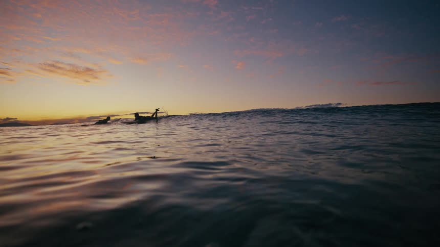 Silhouette of several surfers in the sea on a morning