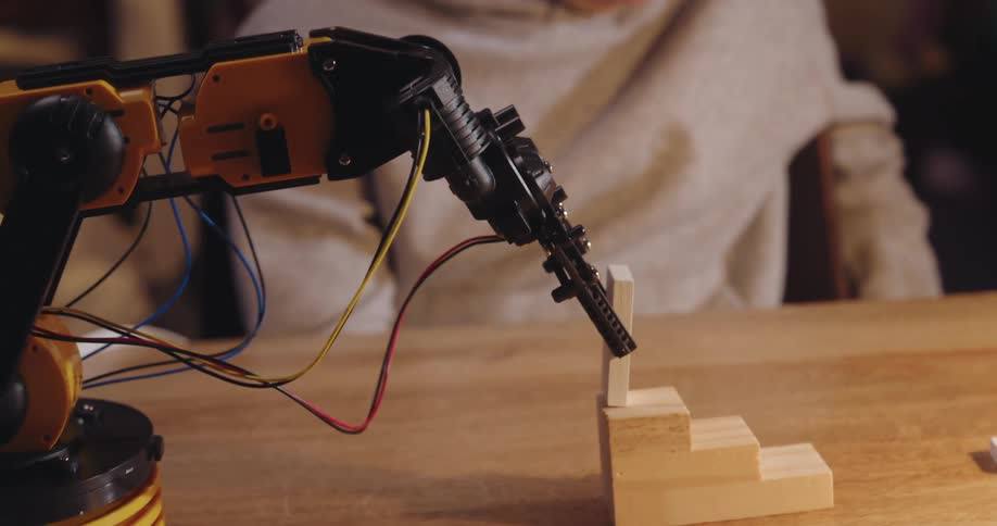 Boy focused on a mechanical arm that stacks objects