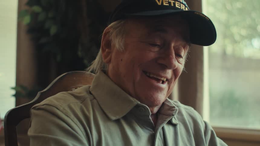 A happy elderly man sitting at home writing a letter