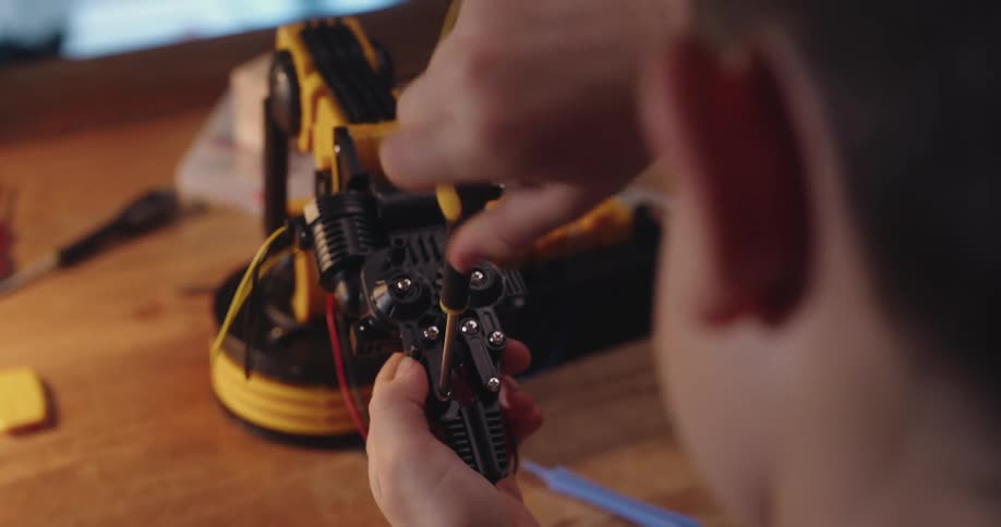 Hands working on intricate equipment with metal parts and wires
