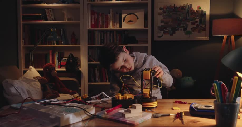 Little boy working on a project with a screwdriver and on top of a table