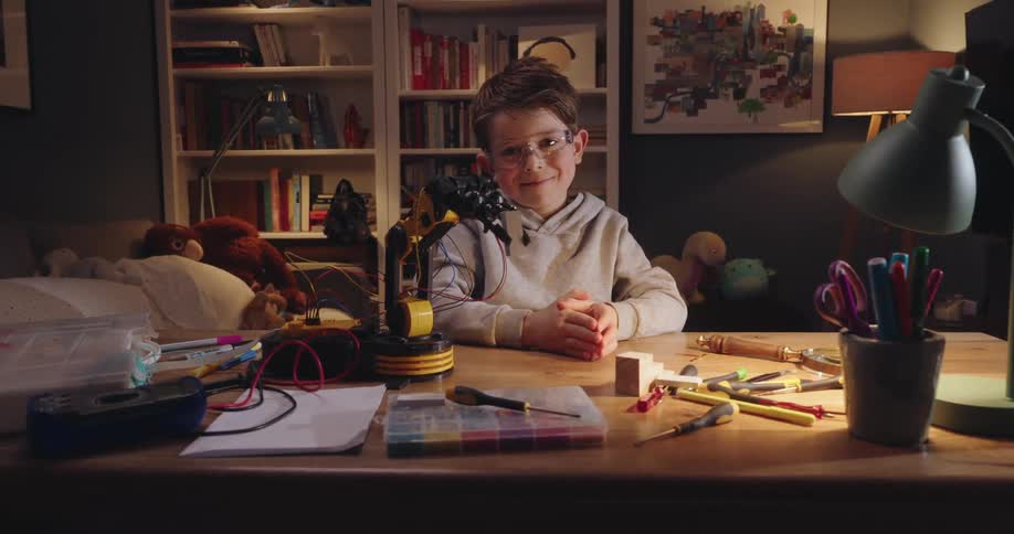 Little boy sitting at a table next to a mechanical arm