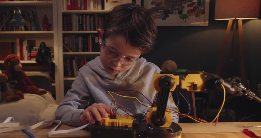 Concentrated little boy working on a mechanical arm project