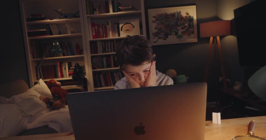 A boy stresses out working on a laptop or tablet at home