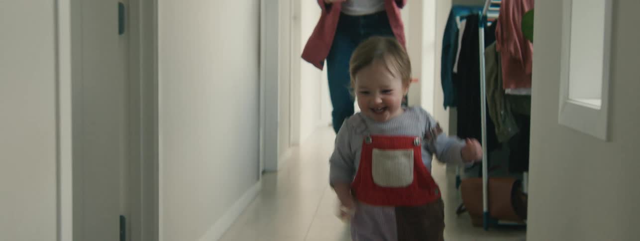 Giggling toddler running down the hallway being chased by his mother