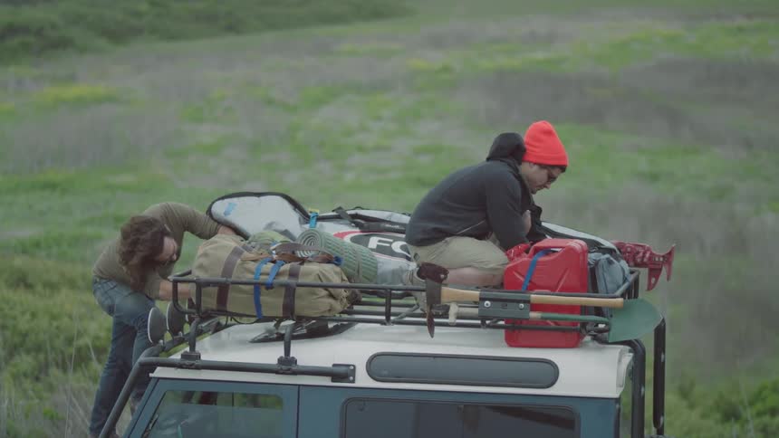Two men looking through their things on top of their truck