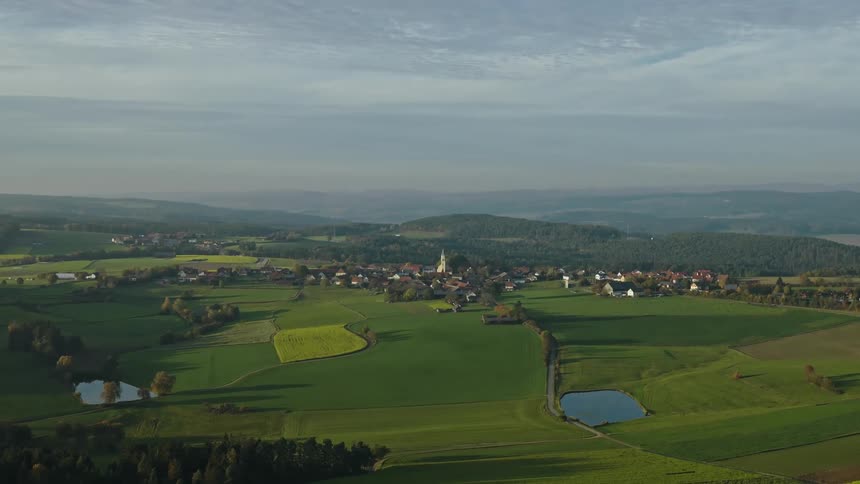 Aerial of a small community surrounded by grassland and forested hills