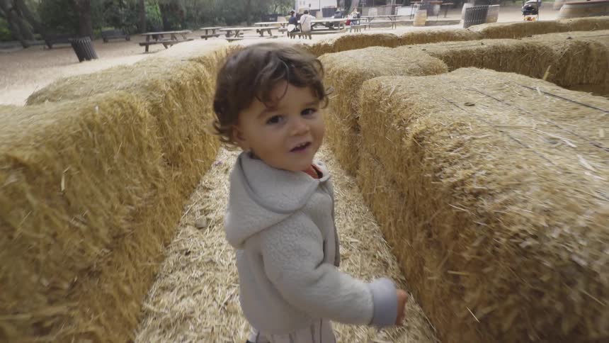 A child is walking through the hay maze