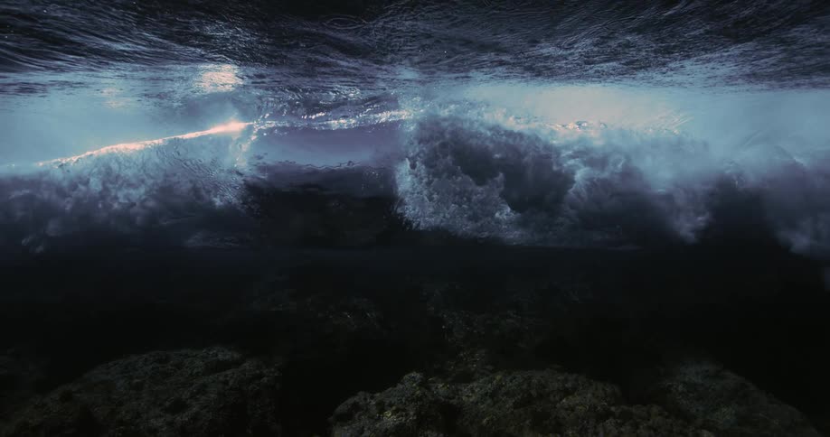 Underwater view of the ocean and a wave breaking with foam