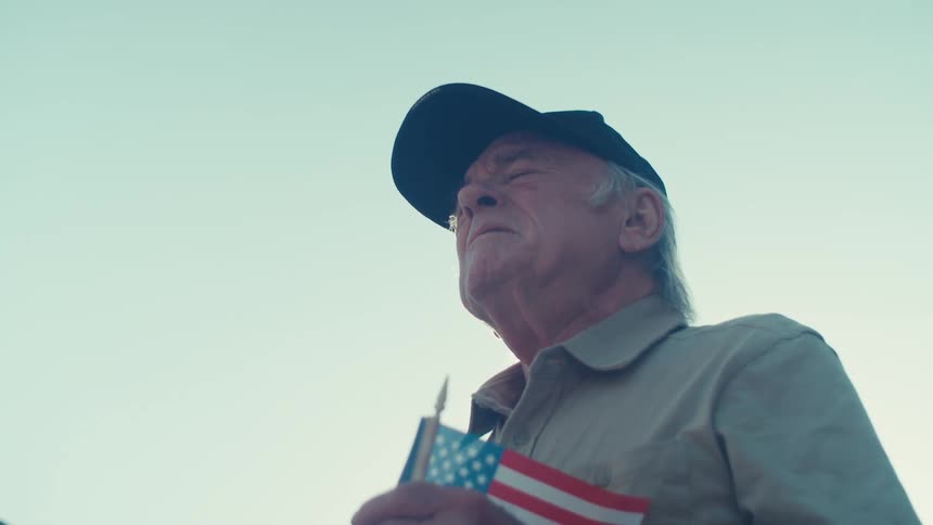 A man is holding a small american flag outside
