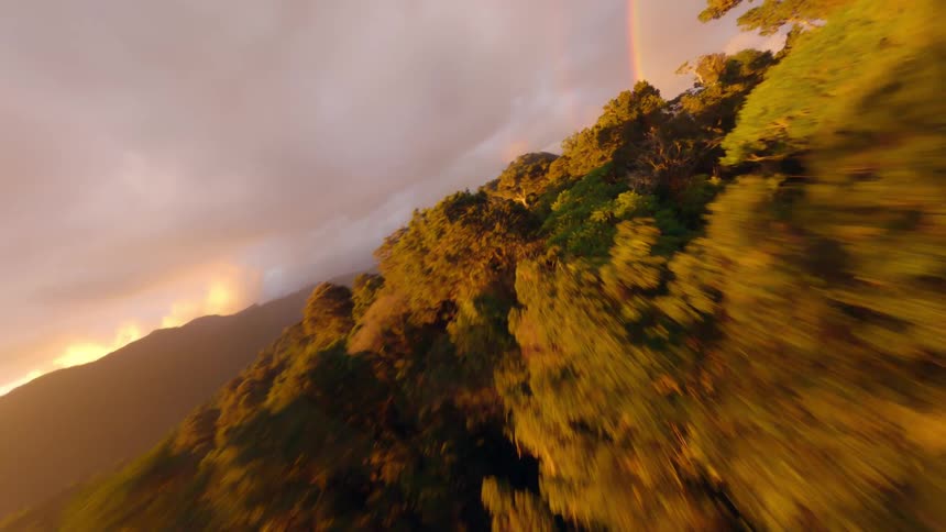 Storm clouds over mountains and forested areas creates a rainbow