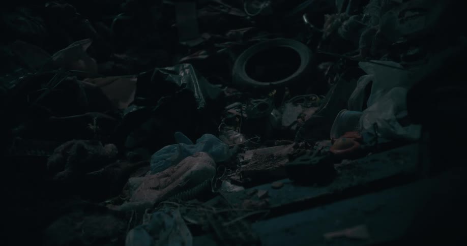 A pile of trash and debris illuminated by a dim light source at night