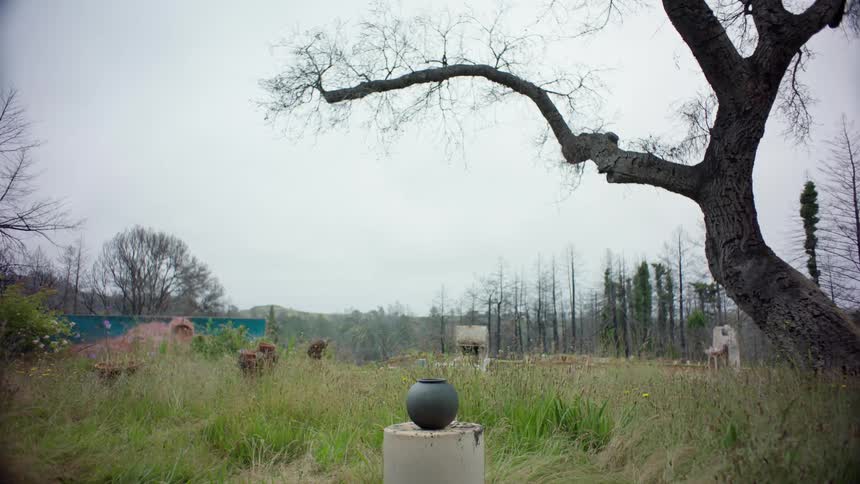 A vase is on a pedestal in the grass