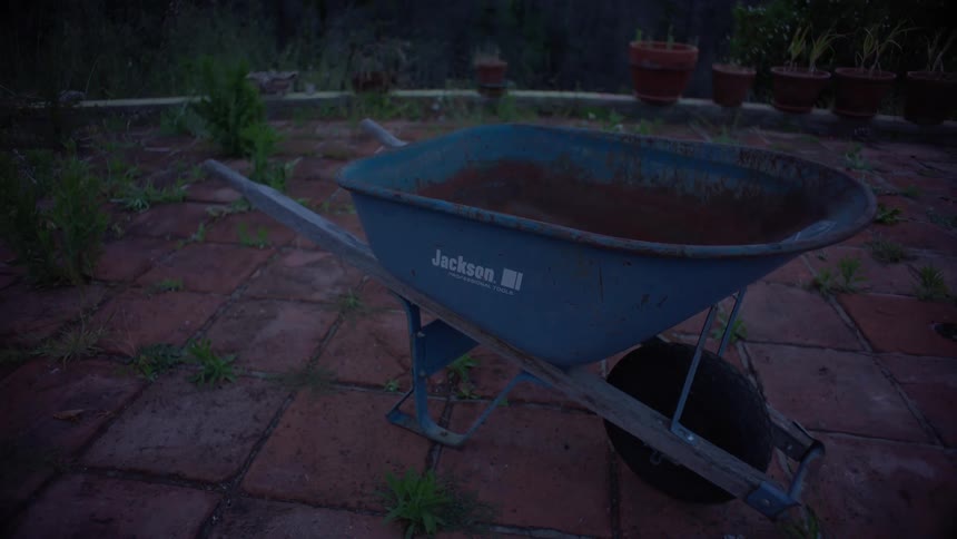A wheelbarrow full of dirt is in the yard