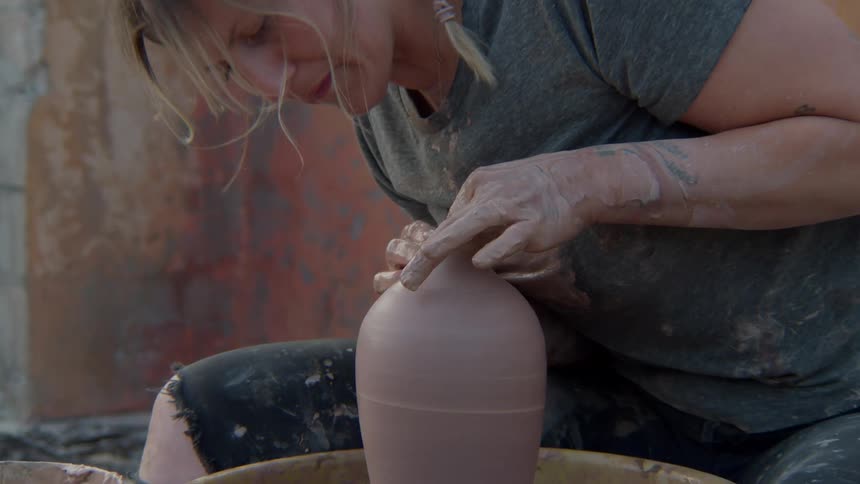 Concentrated woman working on a handmade clay pot