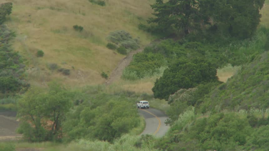 Aerial of a car driving through a hillside in the country