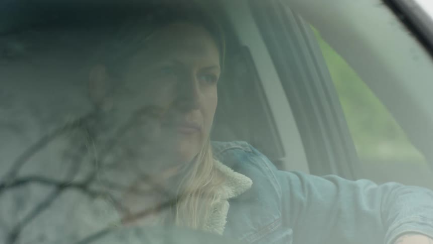 Woman steers her car along a rural highway