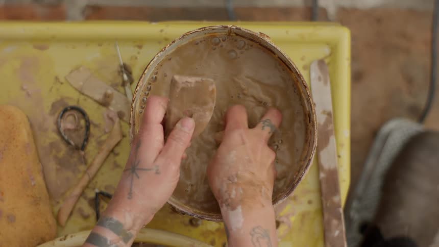 A sculptor washes a tool with a sponge