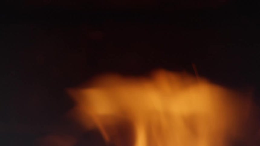 Flames and sparks of a fire contrast with the surrounding darkness