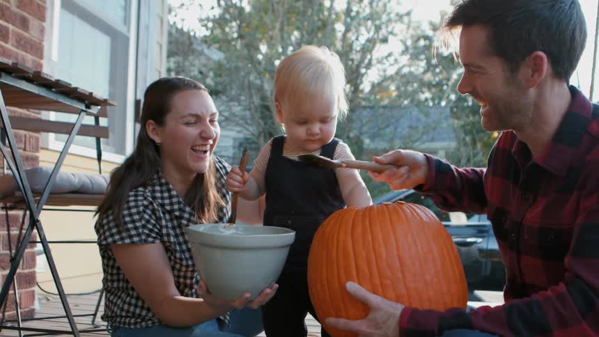 Family on a patio having fun with a pumpkin