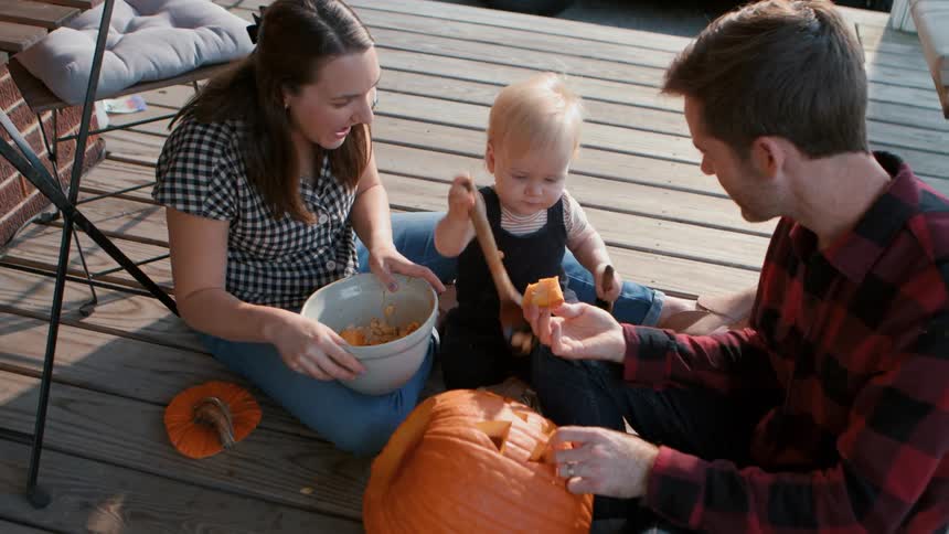 A family carving a jack o lantern on the porch at dusk