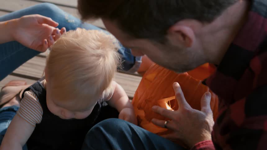 A family carving a jack o lantern on the porch at dusk