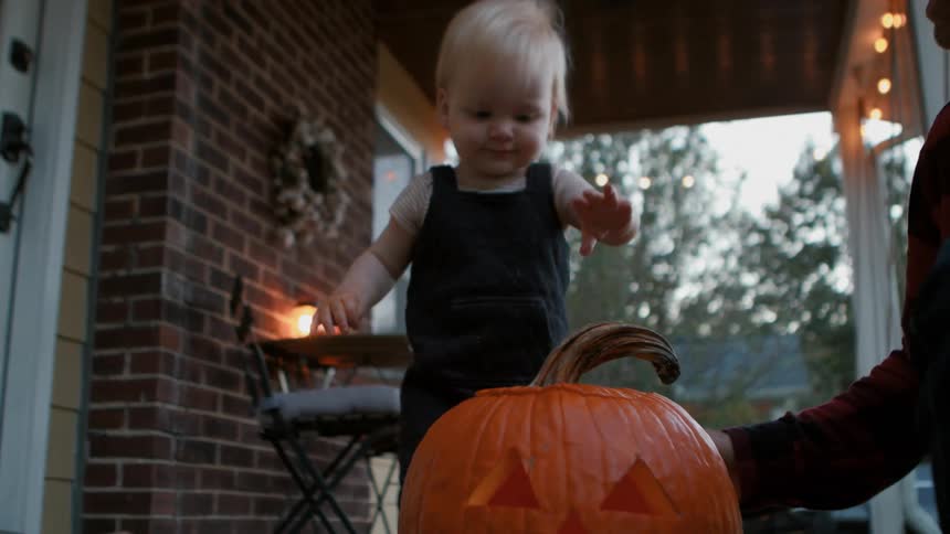 Family with a little boy having fun with a halloween pumpkin