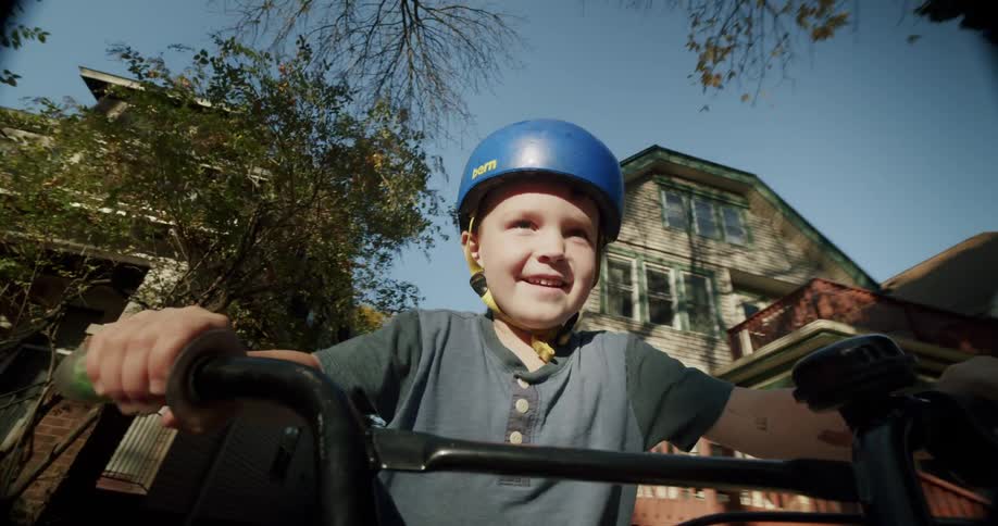 A child wearing a helmet rides a bicycle in the neighborhood during fall