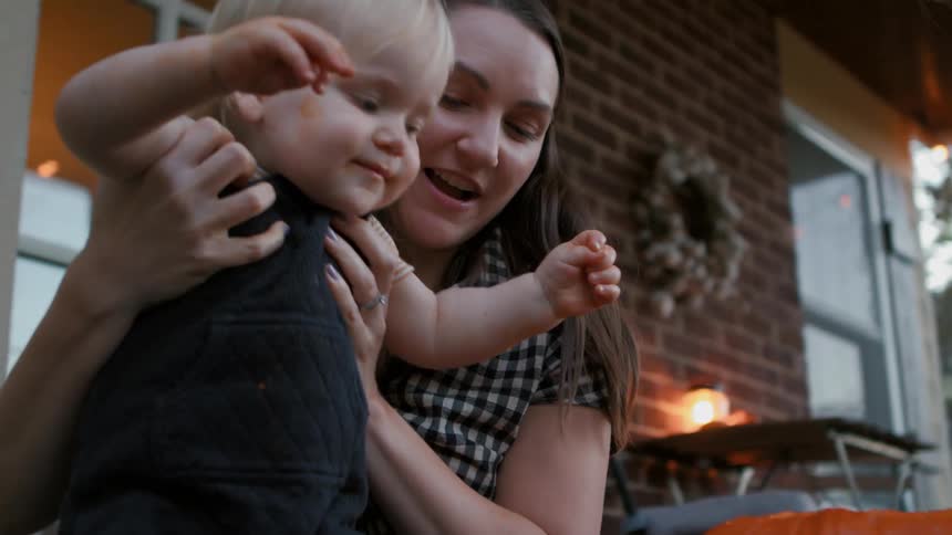 A family carving a jack o lantern on the porch at dusk