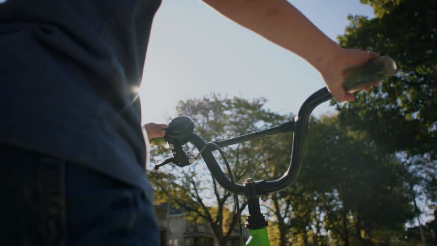 Hands of a little boy holding the handlebars of a bicycle