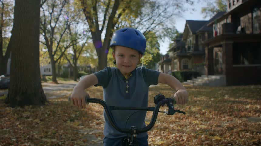 Little boy sitting on his bike while on the sidewalk in a residential neighborhood