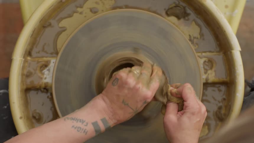 Female potter shaping clay on a pottery wheel makes a mistake