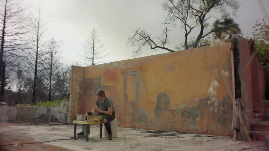 Woman sitting working on a handmade clay vase