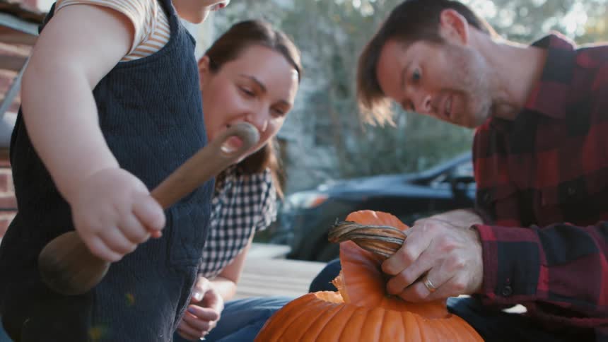 A family is carving a pumpkin on the porch