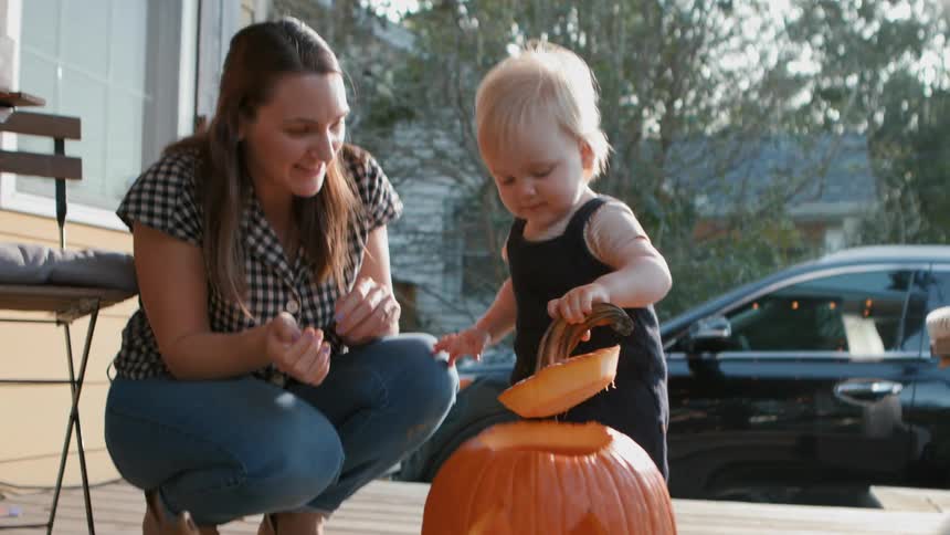 A child removes the lid from a carved pumpkin