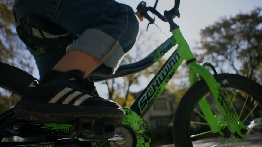 A child sits on a green bicycle ready to ride