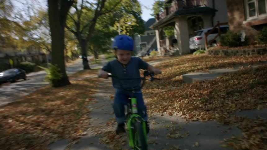 Little boy having fun riding his bike on the sidewalk of a residential neighborhood