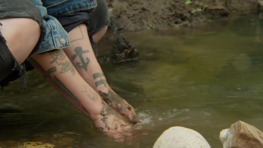A person is cleaning their hands in the stream