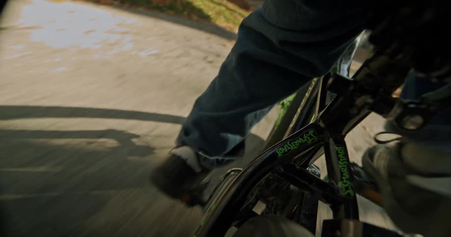 Closeup of a boy riding a bicycle down the sidewalk