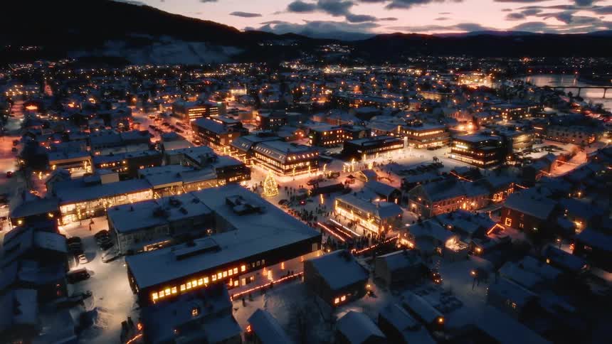 Aerial view of a small town illuminated at night covered in snow with christmas decorations