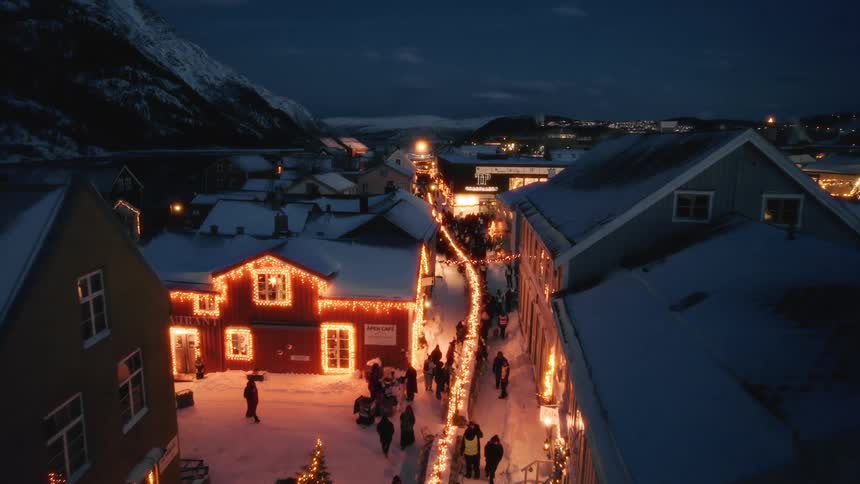 Aerial view of a residential neighborhood on the side of a mountain and illuminated and decorated with christmas lights at night