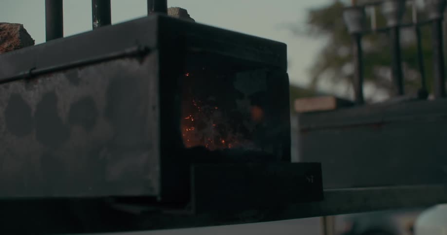 A blacksmith lights up a small outdoors furnace