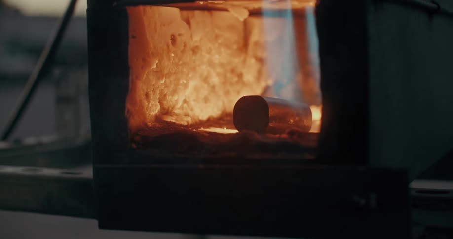 Closeup of metal being tempered in a small forge with a glowing fire inside