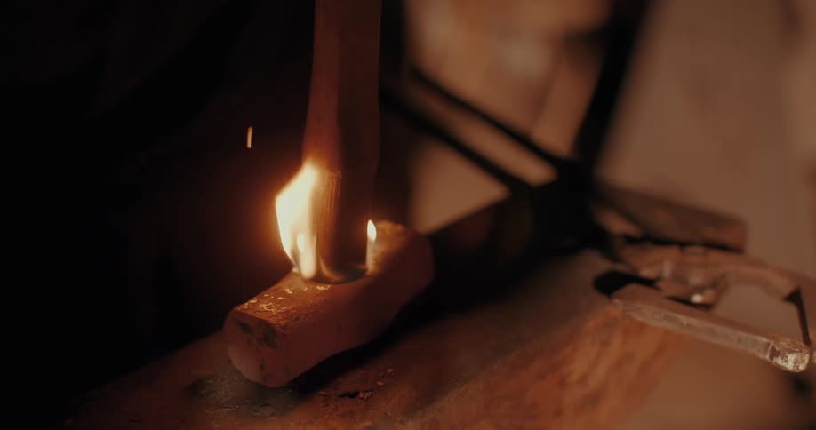 A wooden handle burns from the point where it contacts a metal hammer head