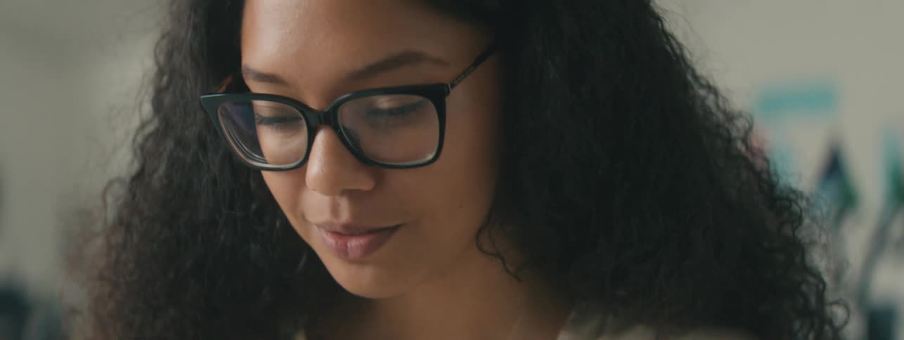 Portrait of a young woman with glasses and curly hair in an indoor space
