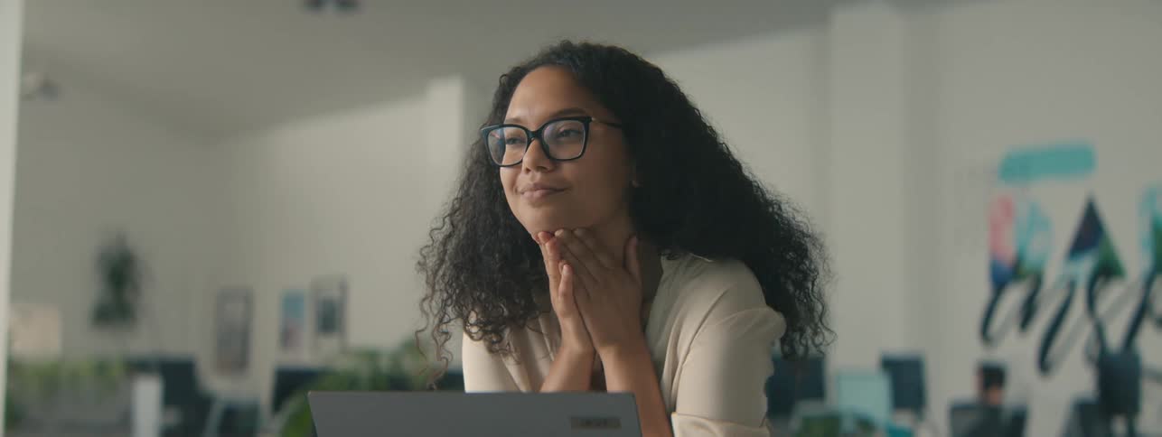 Woman with happy facial expression sitting in front of an open laptop