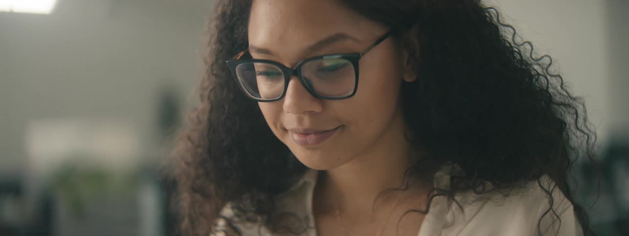 A happy woman with curly hair takes a video call on a laptop in the office