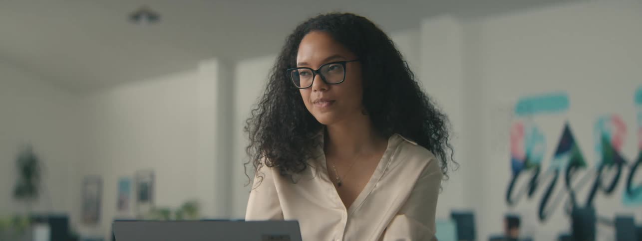 Curly haired woman working on a laptop in an office environment