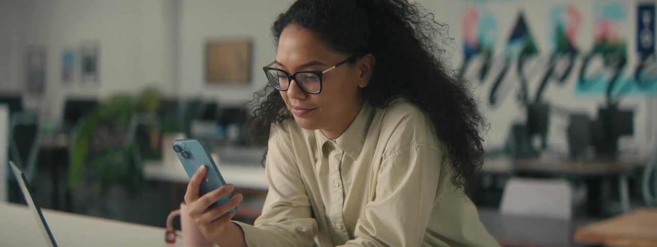Young woman in an office environment interacting with her iphone