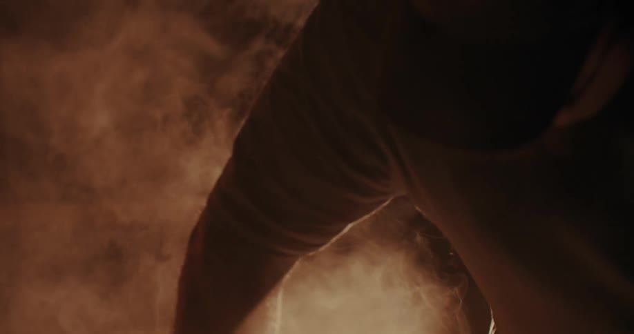 A worker plunges an object held with tongs into a container that emits large amounts of smoke